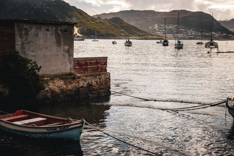 Boats moored in a calm harbor under mountains