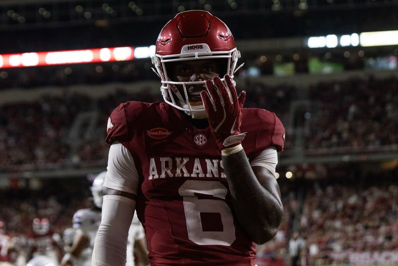 Arkansas player number 6 holds a hand to his face mask under the stadium lights