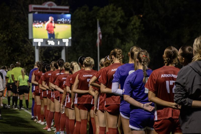 Arkansas soccer players stand in a line at a night game