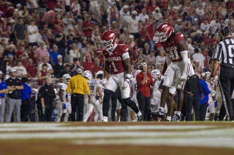 Two Arkansas players celebrate on the sideline as an official looks on